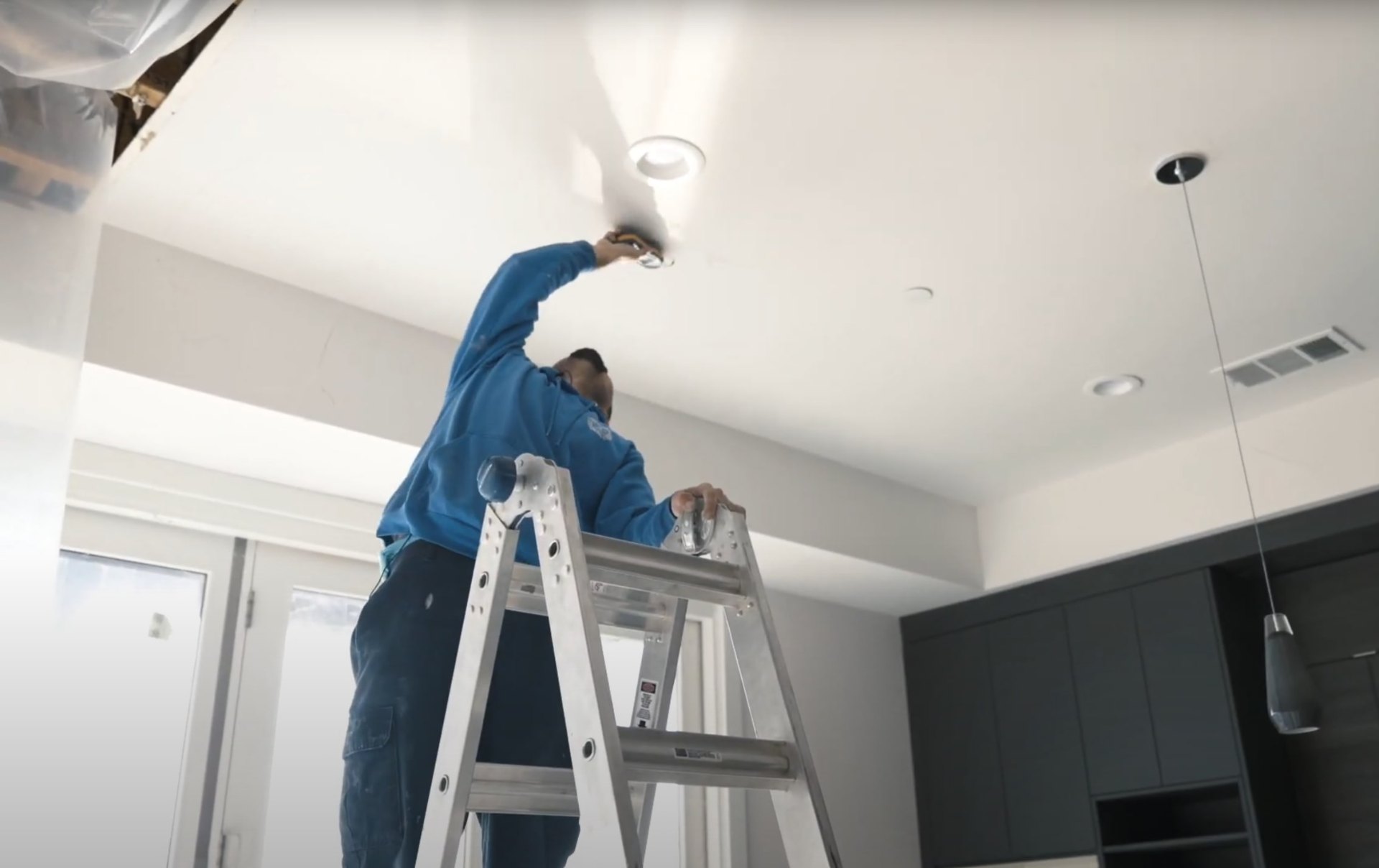 Professional installation of specialized drying equipment for ceiling water damage Technician installing ceiling drying equipment for water damage restoration